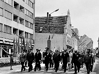 1975-16  1 maja 1975  Jawor, ul. Grunwaldzka  Obchody 1 maja - Święto Pracy    Przedstawiciele władz miasta, partii stacjonującego w mieście 15 batalionu samochodowego Oddziałów Północnej Grupy Wojsk Armii Radzieckiej zmierzający z rynku w kierunku trybuny honorowej.   Piąty od lewej: Eugeniusz Barczyński - I sekretarz Komitetu Powiatowego Polskiej Zjednoczonej Partii Robotniczej (KP PZPR).  Trzeci od lewej w drugim rzędzie w jasnym płaszczu: Jan Wilowski - naczelnik powiatu.