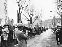 1983-22  1 maja (prawdopodobnie rok 1983)  Jawor, ul. Wyszyńskiego (dawn. Rapackiego)  Obchody 1 maja - Święto Pracy     Uczestnicy pochodu zmierzający w kierunku trybuny honorowej.  Na pierwszym planie: Janusz Kredoszyńński - założyciel i kierownik Jaworskiego Klubu Filmowego "Jawornik" i twórca Jaworskiej Kroniki Filmowej.