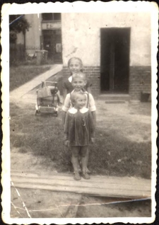 Podw&oacute;rko domu przy ul. Dworcowej 62, od przodu stoją Ewa, Zbyszek i Jola Pawlukowie, ok. 1960 r. [Dokument ikonograficzny]