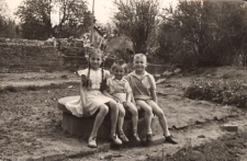 Skrzyżowanie obecnych ulic Skłodowskiej i Dworcowej - na cembrowinie studni siedzą Jola, Ewa i Zbyszek Pawlukowie, ok. 1960 r. [Dokument ikonograficzny]