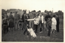 Impreza sobótkowa w Pęgowie : w kapeluszu i okularach telereporter Pęgowskiej Kupalnocki z niezbędnym mobilnym sprzętem w postaci wózka i teleskopu, 23.06.1984 r. [Dokument ikonograficzny]